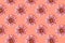 Pattern made of dahlia flower heads on a coral background.