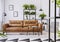 Patterned armchair next to brown leather couch in white living room interior