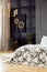 Patterned bed in grey bedroom interior with gold chandelier, black poster and plants