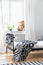 Patterned black and white blanket on bed in bedroom interior with plush toy on window sill