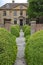 A patterned concrete block walkway between rounded topiary shrubs in an English country garden