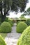 A patterned concrete block walkway between rounded topiary shrubs in an English country garden
