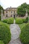 A patterned concrete block walkway between rounded topiary shrubs in an English country garden