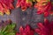 Patterned fall maple leaves, red, green, red, orange, and yellow, on a dark wood background