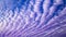 Patterned fluffy purple or ultra violet clouds in blue sky