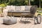 Patterned pouf and rattan chair on wooden patio with pillows on