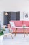 Patterned wooden armchair next to table and pink sofa in living