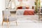 Patterned wooden armchair in red bedroom interior with blanket o