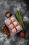 The patties of minced meat on a tray, on black dark stone table background, top view flat lay