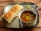 Pav Bhaji is a fast food dish from India, Thick and spicy vegetable curry, served with a soft bread roll or Bun Paav and butter.