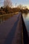 Paved footbridge in a park over a lake at sunset