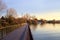 Paved footbridge in a park over a lake at sunset