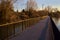 Paved footbridge in a park over a lake at sunset