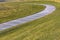 Paved footpath that curves through the grassy terrain viewed on a sunny day