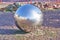 Paved granite pavement is reflected in a metal ball on a sunny day