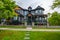 Paved pathway to the entrance of residential house with metal grid gate in front. Dark colored house with fence and entrance gate