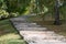 Paved with tiles and cobblestones footpath climbs steps to a wooded hill, park, background