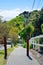 Paved walkway leading down the hill through the lush green of Karori suburb of Wellington, New Zealand on a bright sunny