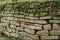 Paved wall with a rough, clear texture and deep lines between large stones. Laying an old fence. Destroyed stone fence