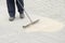 Pavement construction worker filling the block joints with sand using long broom