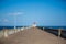 Pavement that leads to a lighthouse captured in coastal North pier on a bright day under a clear sky