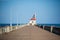 Pavement that leads to a lighthouse captured in coastal North pier on a bright day under a clear sky