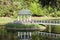 Pavilion in beautiful public garden park. White Gazebo forest view. Outdoor arbor with forged bridge, pond and background of a sum