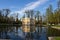 Pavilion `Upper bath` in Catherine Park, mirrored in the water of the pond. Around the trees. Against the blue sky..