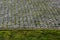 Paving of cubes in a regular grid square pattern. gray granite path with overgrown joints with moss and connected to the lawn. pat