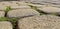 Paving slabs with a grass. Cobblestone striped pathway. Detail of ancient road surface . Grey paving stones closeup.