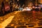 Paving stones on the roadway with glare from night illumination. View from sidewalk level. Selective focus