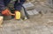 Paving the tiles on the sidewalk, the worker lay the tile, aligning it on the thread