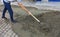 Paving the tiles on the sidewalk, the worker leveling the foundation with a construction shovel