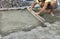 Paving the tiles on the sidewalk, the worker leveling the foundation with a wooden board