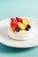 Pavlov`s meringue cake with cream and glazed fruit on turquoise tablecloth
