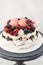 Pavlova cake with whipped cream, raspberry, blueberry, blackberry and french macaroons. Copy space, plain background