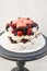 Pavlova cake with whipped cream, raspberry, blueberry, blackberry and french macaroons. Copy space, plain background