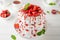 Pavlova layered cake with fresh strawberries, sauce and whipped cream on a white wooden background. Summer beautiful cake.