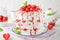 Pavlova layered cake with fresh strawberries, sauce and whipped cream on a white wooden background. Summer beautiful cake.