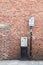 Pay and Display parking meter with information sign on a pole in front of the red brick wall