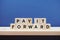 Pay It Forward alphabet letter on blue and wooden shelves background