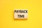 Payback time symbol. Concept words Payback time on wooden blocks. Beautiful yellow table yellow background. Business and payback