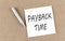 PAYBACK TIME text on sticky note on a cork board with pencil