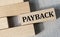 PAYBACK - word on a wooden bar on a gray background