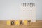 Payday loan concept. Flipped wooden cube block with yellow and grey pay day text and blurred white calendar on wood desk