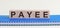 PAYEE - a word made of wooden blocks with black letters, a row of blocks is located on a blue Notepad. White background, front