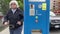 paying for parking in the city of Victoria a gray-haired American woman approaches the machine with a card in her hands