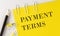 PAYMENT TERMS word on the yellow paper with office tools on white background