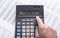 PAYMENTS word on calculator display on financial documents, male hand ponting at the insciption