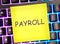 PAYROLL word on a yellow sticker on a colored backlit keyboard